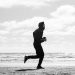 Silhouette of a jogger running along La Lucila del Mar beach, captured in monochrome.